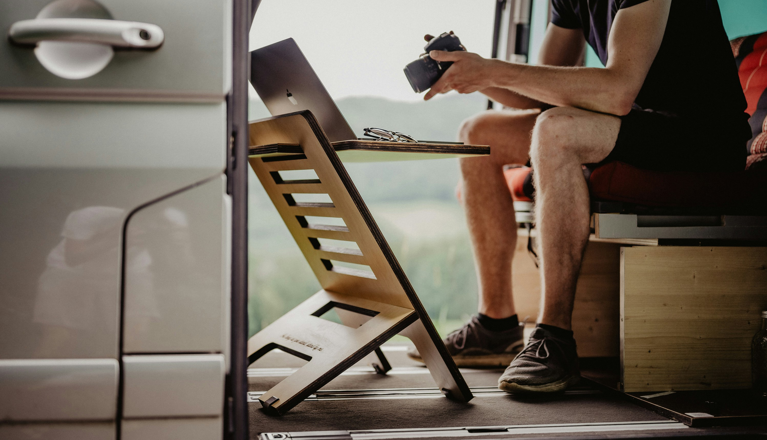 Les modes de vie polyvalents engendrent des occasions d'afffaires Un voyageur est assis dans son van et regarde l'écran de son appareil photo avec son ordinateur installé sur une petite table en face de lui