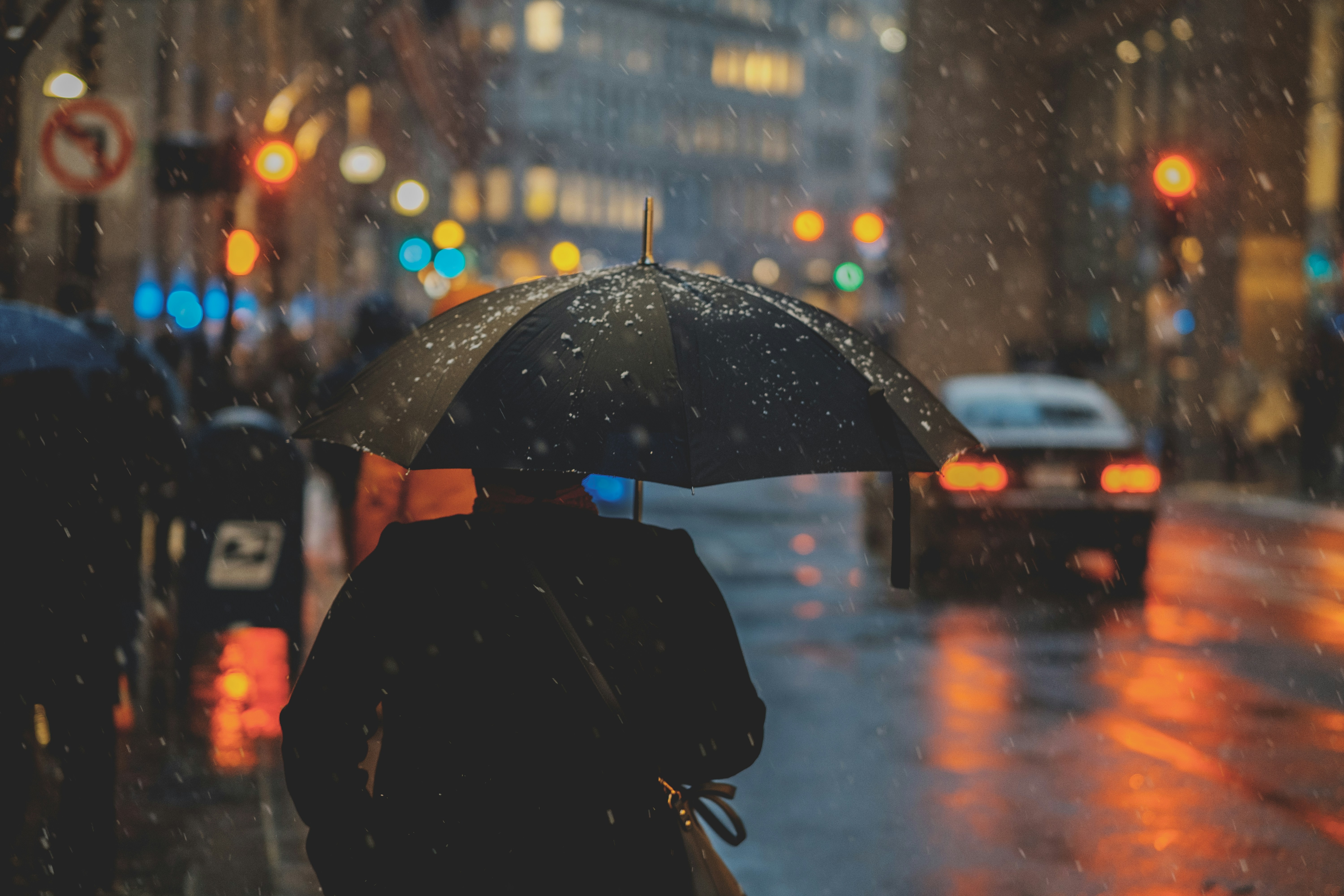 Composer avec des événements météorologiques extrêmes Un homme avec un parapluie ouvert au-dessus de la tête marche en ville sous la pluie